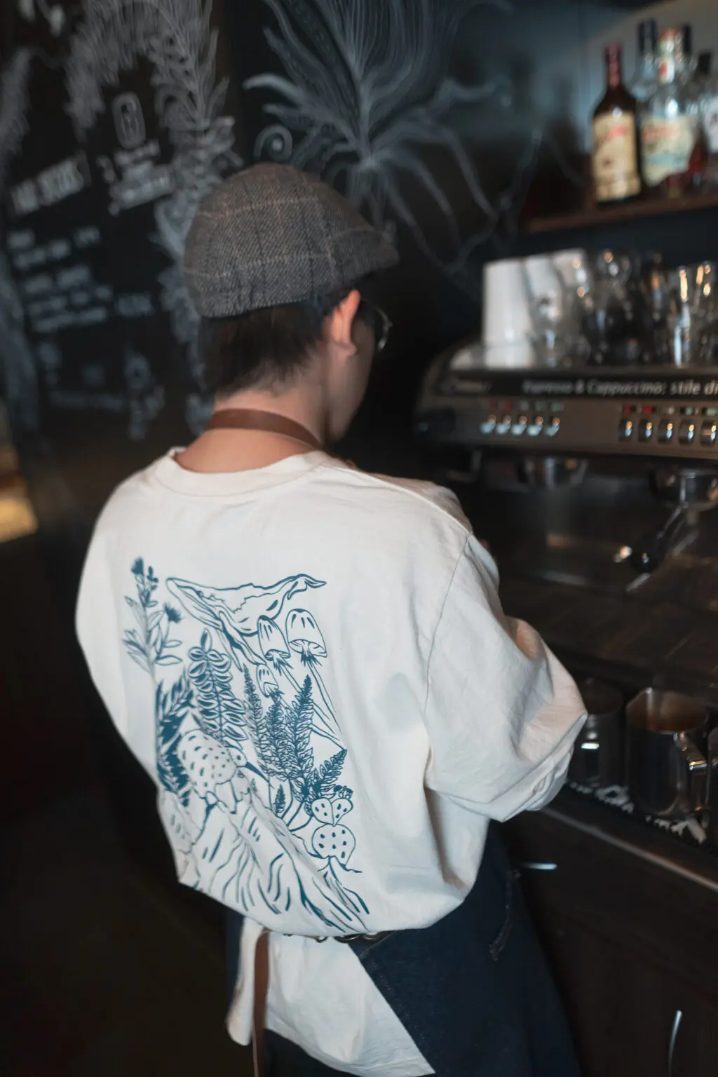Barista im kiwis-Pullover an der Kaffeemaschine