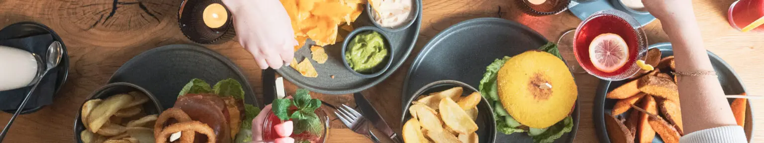 Gedeckter Tisch von oben mit Burgern, Pommes und Dips