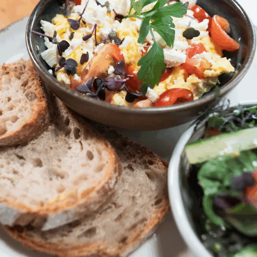 Rührei mit Tomaten und Kräutern, dazu Brot und Salat