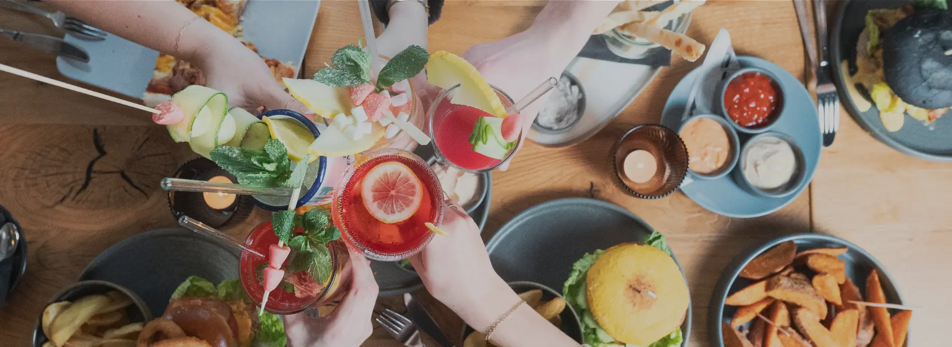 Freunde stoßen über einem gedeckten Tisch mit Drinks an