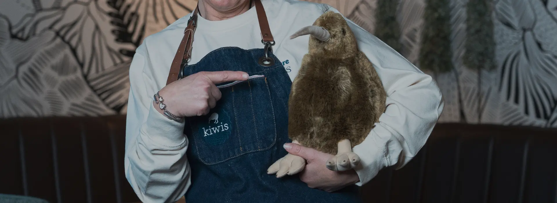 Mitarbeiterin zeigt auf den Kiwi-Plüschvogel